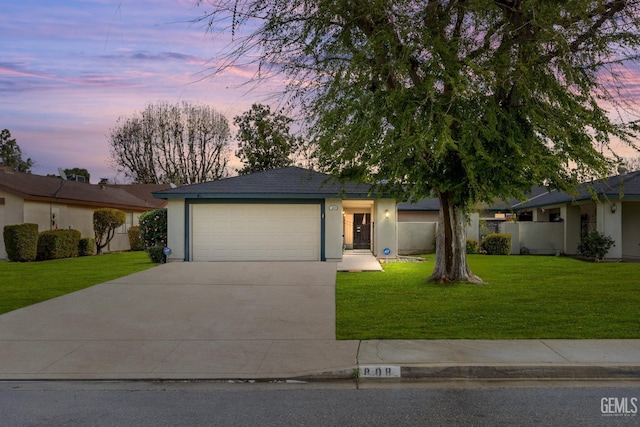 ranch-style home featuring a garage, driveway, a front yard, and stucco siding