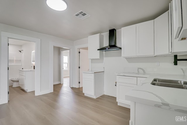 710 Fillmore St, Taft, CA 93268 - kitchen featuring light wood-style flooring, visible vents, a sink, white cabinetry, and wall chimney exhaust hood