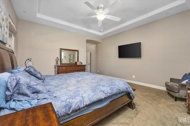 carpeted bedroom with a tray ceiling and ceiling fan