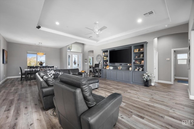 living room with a tray ceiling, ceiling fan, and hardwood / wood-style flooring