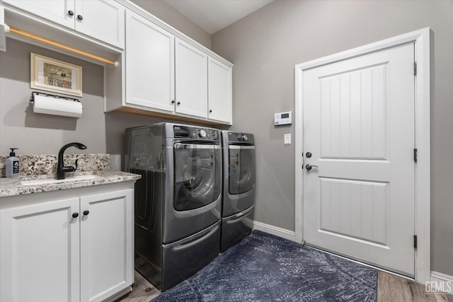 clothes washing area featuring washer and dryer, dark hardwood / wood-style floors, cabinets, and sink