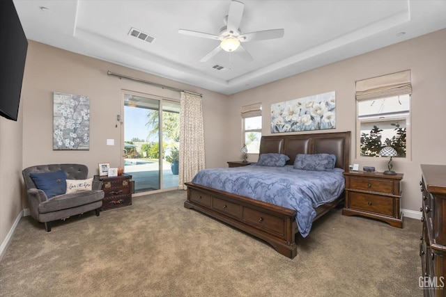 carpeted bedroom featuring a raised ceiling, access to exterior, and ceiling fan