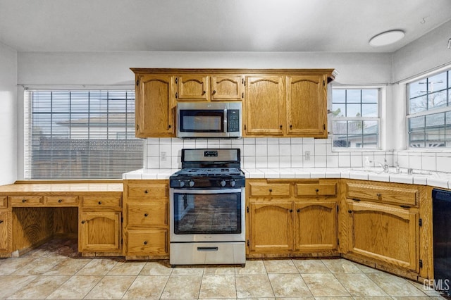 kitchen with sink, stainless steel appliances, tile countertops, and backsplash