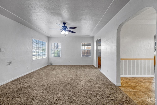 unfurnished room featuring a wealth of natural light, ceiling fan, carpet flooring, and a textured ceiling