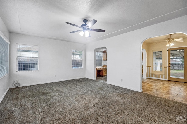 empty room featuring ceiling fan, carpet flooring, a textured ceiling, and a wealth of natural light