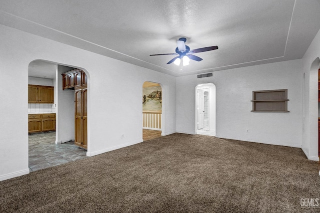 unfurnished living room with ceiling fan, a textured ceiling, and light colored carpet