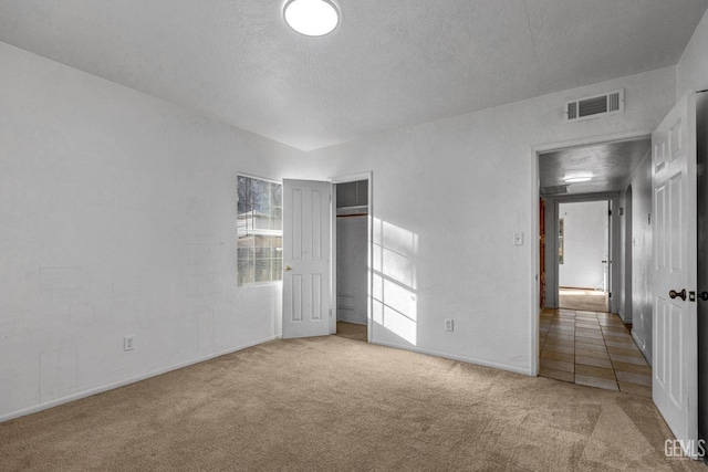 unfurnished bedroom featuring carpet, a textured ceiling, and a closet