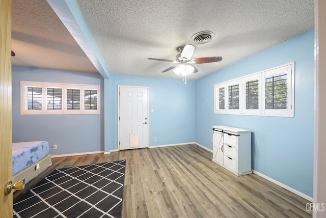 6513 Desmond Ct, Bakersfield, CA 93308 - unfurnished bedroom featuring a textured ceiling, multiple windows, wood finished floors, and ceiling fan
