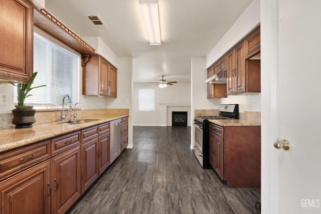 kitchen featuring light stone countertops, ceiling fan, sink, dark wood-type flooring, and appliances with stainless steel finishes