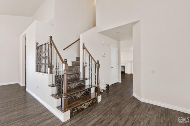 stairway with hardwood / wood-style flooring and a towering ceiling