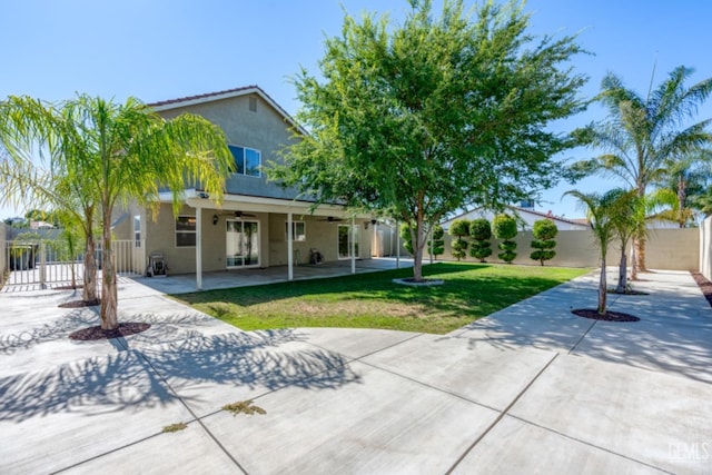 back of property with a lawn, ceiling fan, and a patio