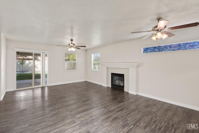 unfurnished living room with a textured ceiling, plenty of natural light, dark wood-type flooring, and ceiling fan