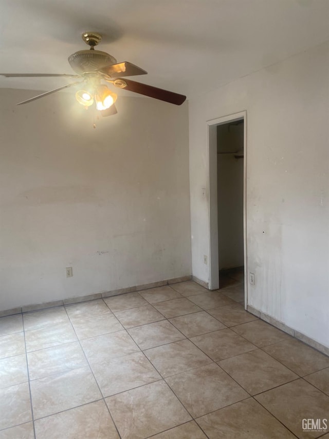 empty room featuring light tile patterned floors, baseboards, and a ceiling fan