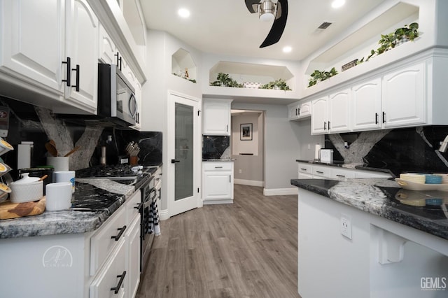 kitchen with tasteful backsplash, visible vents, a ceiling fan, light wood-style flooring, and white cabinetry