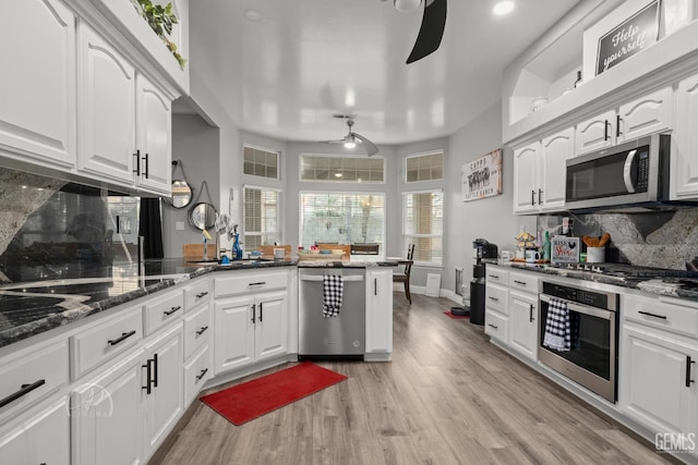 kitchen with white cabinets, appliances with stainless steel finishes, a ceiling fan, and light wood-style floors