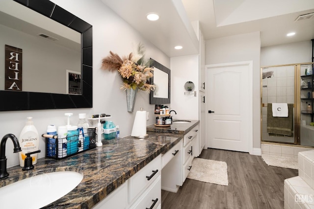 kitchen featuring dark wood-style floors, white cabinetry, a sink, and visible vents