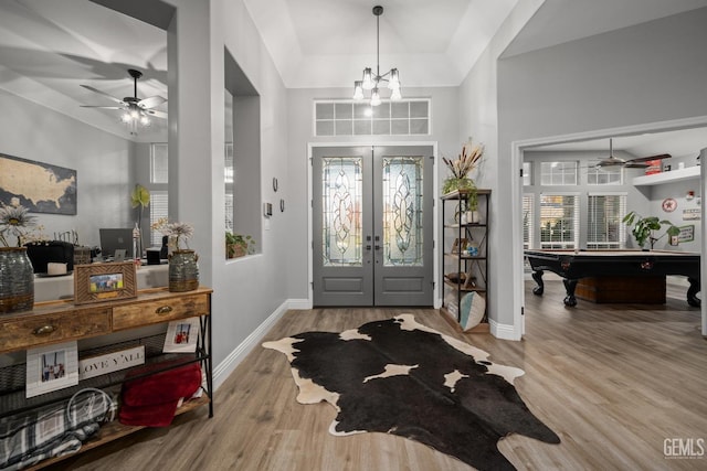 foyer entrance with billiards, baseboards, wood finished floors, french doors, and ceiling fan with notable chandelier