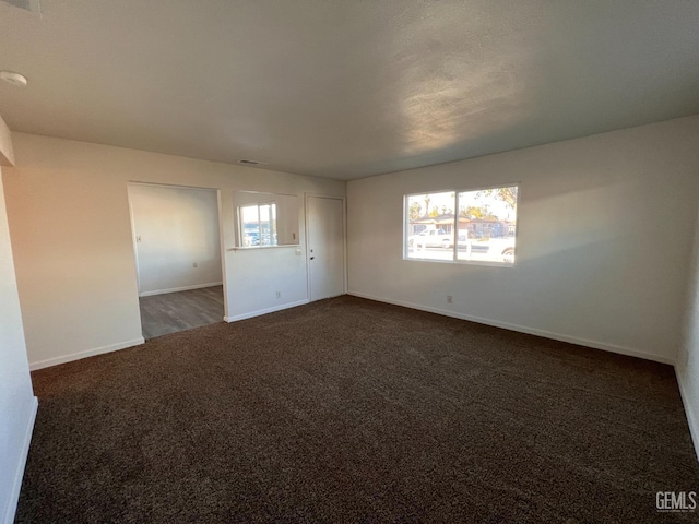 spare room with a healthy amount of sunlight and dark carpet