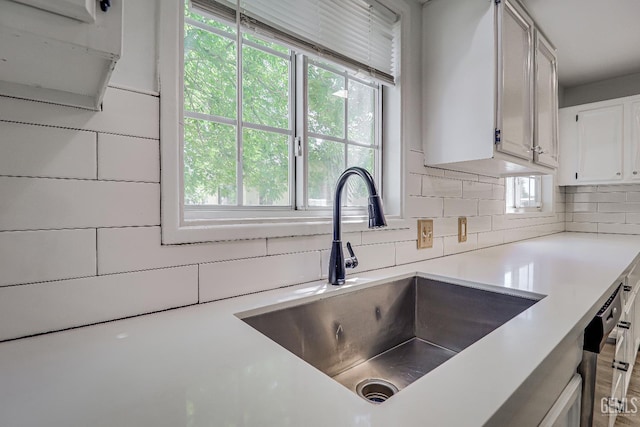 201 Cedar St, Bakersfield, CA 93304 - kitchen featuring a sink, backsplash, light countertops, and white cabinets