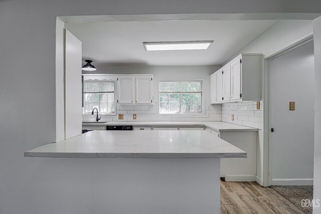 201 Cedar St, Bakersfield, CA 93304 - kitchen with a sink, decorative backsplash, a peninsula, light wood-style flooring, and white cabinetry