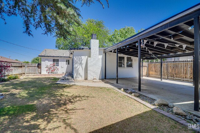 201 Cedar St, Bakersfield, CA 93304 - back of house with a chimney, a carport, stucco siding, and a patio