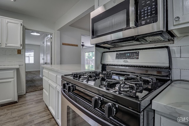 201 Cedar St, Bakersfield, CA 93304 - kitchen with stainless steel appliances, white cabinetry, light wood-type flooring, light stone countertops, and a ceiling fan