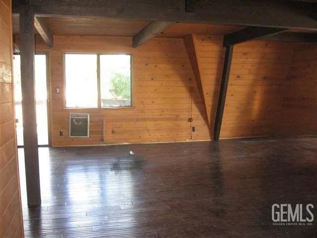 additional living space featuring beamed ceiling, wood walls, dark hardwood / wood-style flooring, and wood ceiling