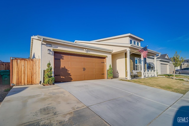 view of front of home featuring concrete driveway, an attached garage, fence, and stucco siding