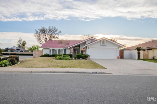 view of front of property featuring driveway, a garage, a tiled roof, a front yard, and stucco siding