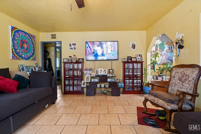 living room with a textured ceiling, ceiling fan, and tile patterned floors