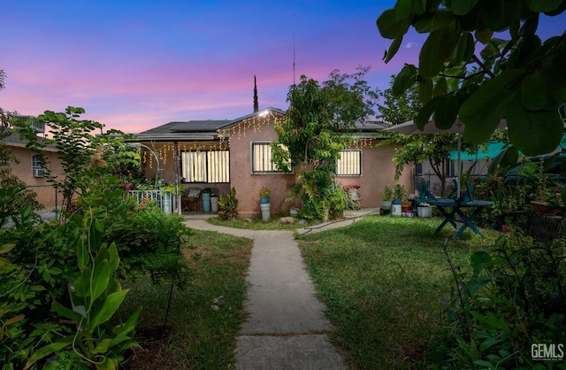 back house at dusk with a lawn and solar panels