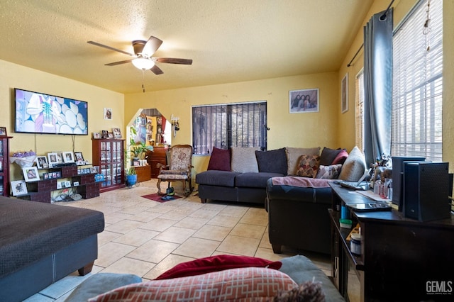 tiled living room featuring a textured ceiling, ceiling fan, and plenty of natural light