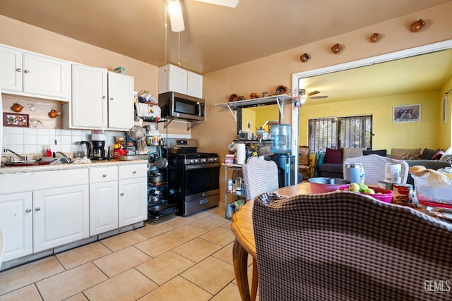 kitchen with light tile patterned floors, white cabinetry, ceiling fan, appliances with stainless steel finishes, and tasteful backsplash