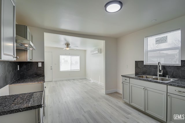 kitchen featuring sink, decorative backsplash, ceiling fan, a wall mounted AC, and light hardwood / wood-style floors