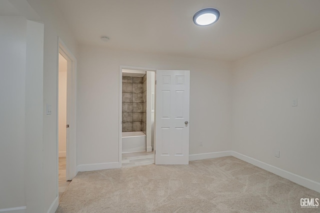 unfurnished bedroom with ensuite bath and light carpet