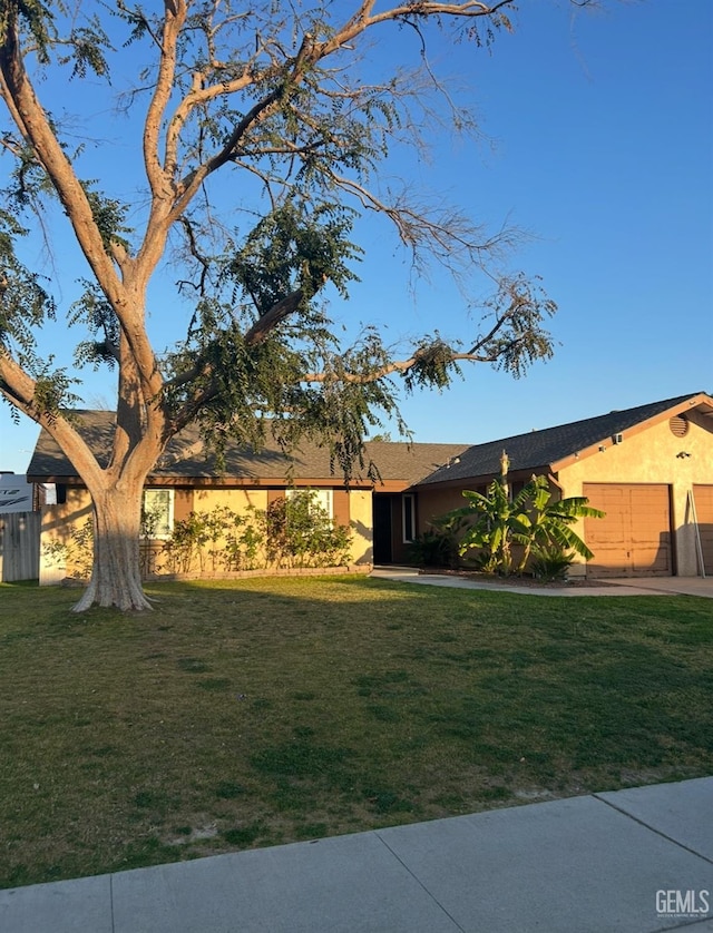 view of front of property featuring stucco siding, an attached garage, and a front lawn