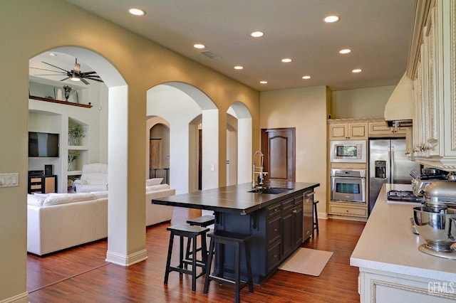 1881 Richert Ave, Clovis, CA 93611 - kitchen featuring appliances with stainless steel finishes, cream cabinetry, recessed lighting, a kitchen breakfast bar, and dark wood-style floors
