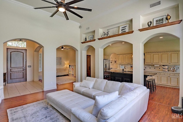 1881 Richert Ave, Clovis, CA 93611 - living area with ceiling fan, crown molding, a towering ceiling, wood finished floors, and arched walkways