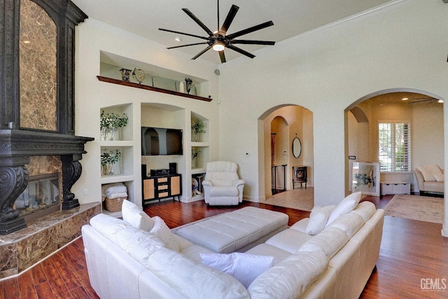 1881 Richert Ave, Clovis, CA 93611 - living room featuring built in shelves, a ceiling fan, wood finished floors, arched walkways, and a glass covered fireplace