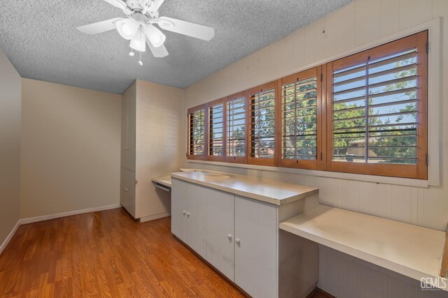 1191 Edmund St, Bakersfield, CA 93309 - kitchen with a textured ceiling, light countertops, light wood-type flooring, white cabinetry, and a ceiling fan