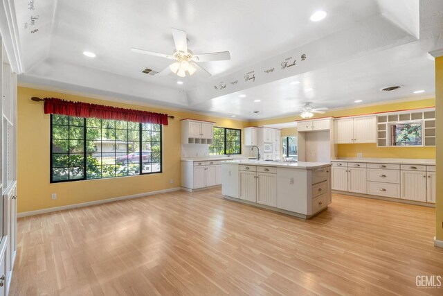 1191 Edmund St, Bakersfield, CA 93309 - kitchen featuring a raised ceiling, ceiling fan, light wood-style floors, light countertops, and crown molding