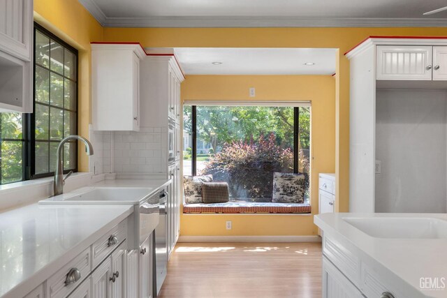1191 Edmund St, Bakersfield, CA 93309 - kitchen featuring light countertops, white cabinets, light wood-style floors, tasteful backsplash, and stainless steel appliances