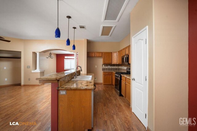5605 Meadow Valley Ct, Bakersfield, CA 93312 - kitchen featuring appliances with stainless steel finishes, a sink, brown cabinets, arched walkways, and wood finished floors