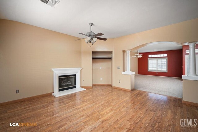5605 Meadow Valley Ct, Bakersfield, CA 93312 - unfurnished living room with ornate columns, a ceiling fan, arched walkways, wood finished floors, and a fireplace with raised hearth