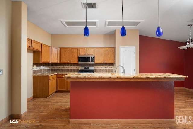 5605 Meadow Valley Ct, Bakersfield, CA 93312 - kitchen with stainless steel appliances, brown cabinets, light wood-type flooring, and backsplash