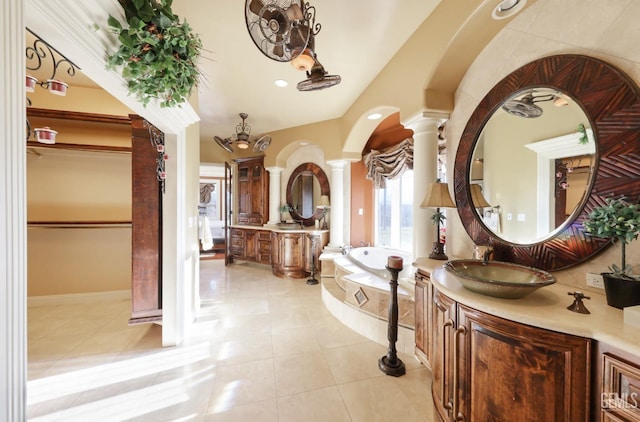 bathroom featuring decorative columns, a relaxing tiled tub, vanity, and tile patterned flooring