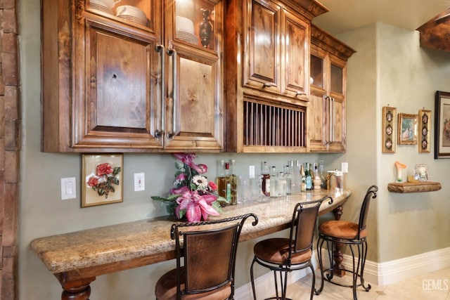 kitchen featuring light stone countertops, a breakfast bar, and light tile patterned flooring