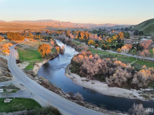 aerial view at dusk featuring a water and mountain view