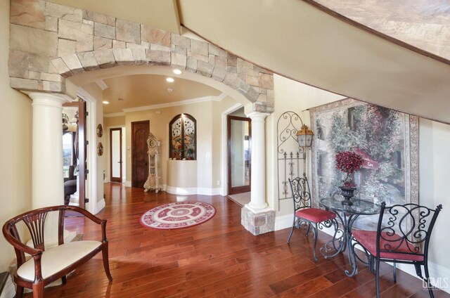 interior space with decorative columns, wood-type flooring, and ornamental molding