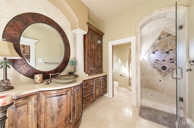 bathroom with toilet, a shower with door, decorative columns, tile patterned floors, and vanity